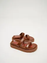 Sandalias de cuero vacuno color marrón con acabado brillante, diseño de dos tiras anchas acolchadas y plataforma baja.