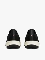 Zapatillas deportivas negras de corte bajo y estilo calcetín, con exterior de punto elástico. Cuentan con cordones, entresuela gruesa color crema y suela de goma negra. Presentan un pequeño logo de Tommy Hilfiger bordado en el lateral.