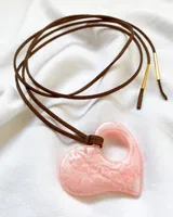 Gargantilla tipo choker con tiento de gamuza marrón y dije de resina rosa con forma de corazón.