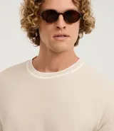 Remera de corte regular confeccionada en tejido texturizado de algodón y poliéster. Presenta cuello redondo y bordes de mangas con detalle de rayas contrastantes en blanco y gris.