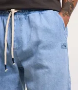 Bermuda de jeans de hombre, color negro con efecto desgastado o acid wash, de corte holgado. Posee cintura elástica con cordón de ajuste y bolsillos laterales.