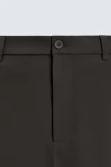 Pantalón de corte regular fit, color negro, confeccionado en tejido elástico. Presenta cintura elástica, cierre frontal con cremallera y botón, bolsillos laterales y bolsillos traseros de vivo.