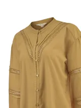 Blusa manga larga de algodón orgánico color tostado, con cuello mao y cierre frontal de botones. Presenta detalles de encaje calado en V sobre el pecho y en las mangas.
