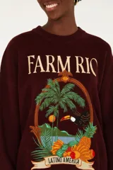 Sweater de punto oversized bordó con cuello redondo y mangas largas con terminaciones acanaladas. Presenta un estampado frontal de estilo tropical con el texto 'Farm Rio' y 'Latino America', acompañado de ilustraciones de una palmera, un tucán y frutas.
