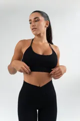 Top deportivo de tejido acanalado en color negro, con diseño de cuello halter y espalda descubierta.