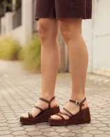 Sandalias de cuero color marrón chocolate con plataforma y tacón cuña revestido, tiras delgadas en el empeine y cierre de hebilla en el tobillo.