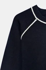 Jersey de punto de manga larga con cuello redondo, diseño en color azul marino con detalles de vivo en color blanco en el cuello y las costuras de las mangas.