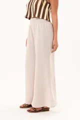 Pantalón palazzo beige de tiro alto, con cintura elástica fruncida y diseño amplio de pernera ancha.