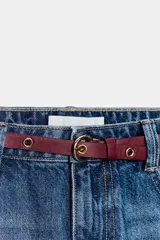 Jeans de tiro alto con corte de pierna recta y diseño de cinco bolsillos. Confeccionados en tejido denim rígido de lavado claro, incluyen un cinturón fino de cuero en tono marrón.