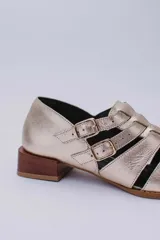 Sandalias bajas de cuero color dorado con tiras entrecruzadas y hebillas ajustables. Taco de madera.