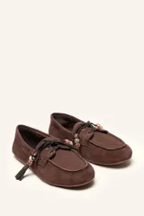 Mocasín estilo náutico de gamuza marrón, con cordones de cuero, borla decorativa y cuentas de colores en el empeine.
