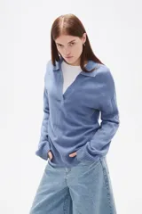 Sweater de punto color azul, con cuello polo y escote en V, de manga larga y diseño holgado.