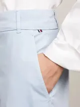 Pantalón chino celeste de corte recto y slim fit, con cierre de cremallera y botón, bolsillos delanteros de parche y logo de Tommy Hilfiger bordado en la parte trasera.