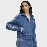 Campera Adidas modelo Firebird confeccionada en tejido denim de algodón. Presenta cierre frontal de cremallera, cuello alto, puños y ruedo en tejido rib elástico. Incluye las icónicas tres franjas en las mangas y el logo del trébol bordado en el pecho.