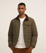 Campera puffer masculina de color verde oliva, con cierre frontal de botones a presión, cuello de pana en contraste y bolsillo tipo cargo en el pecho. Presenta un diseño acolchado horizontal y forro interior suave.
