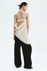 Top strapless de satén color beige, con diseño ceñido, drapeado lateral en la cintura y bajo asimétrico.