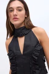 Top de lino color beige, sin mangas, con cuello alto halter y detalles de volados frontales.