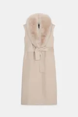 Chaleco largo de mezcla de lana color beige, de corte recto con manga sisa. Cuenta con cuello solapa con aplicación de pelo sintético extraíble, bolsillos laterales ocultos y un cinturón ajustable del mismo tejido para anudar en la cintura.