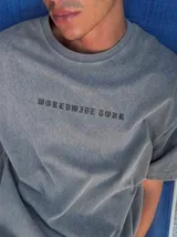 Remera oversize gris con efecto acid wash y estampa frontal con la leyenda "WORLDWIDE TOUR" en tipografía gótica.