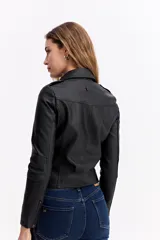 Campera estilo biker de cuero sintético negro, con cierre frontal asimétrico, solapas con broches metálicos y bolsillos laterales con cierre.