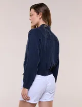 Camperita bomber de lyocell con textura suave, color azul marino, cuello camisero, cierre frontal con botones a presión, bolsillos laterales con solapa, mangas largas con puños elásticos y pretina fruncida en el ruedo.