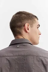 Camisa de manga larga color gris oscuro, confeccionada en tejido liviano con textura sutil, cuello tradicional y cierre frontal de botones.