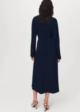 Vestido midi de corte evasé en color azul marino, con cuello camisero, cierre frontal de botones ocultos y mangas largas con puños abotonados. Incluye un cinturón fino ajustable con hebilla metálica.