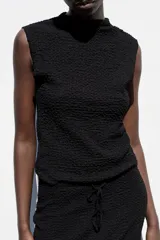 Top negro sin mangas, con cuello perkins y tejido texturizado.