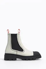 Botín Chelsea de cuero color rosa con puntera y suela track color negro. Cuenta con elásticos laterales negros y tiradores en la parte trasera.