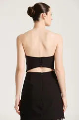 Vestido largo negro de fiesta, con diseño strapless, cuerpo corto entallado y falda larga semitransparente de encaje con abertura lateral pronunciada. Incluye gargantilla a juego.