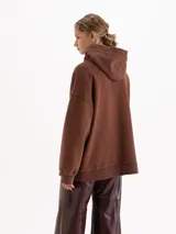 Buzo marrón de corte amplio con capucha forrada en corderito. Presenta una estampa frontal de un conejo rojo haciendo una burbuja de chicle, parte de la cápsula Il Bunny Porta Fortuna.