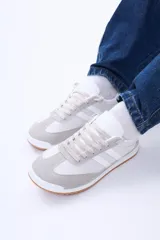 Championes urbanos de diseño retro, combinan paneles de gamuza gris en la puntera y talón con cuerpo de material sintético negro. Presentan dos franjas laterales blancas, cordones negros y suela de goma con base color caramelo.