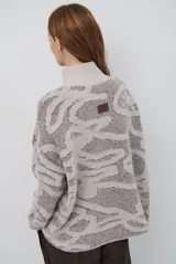 Buzo de tejido de punto con cierre frontal, cuello alto y diseño estampado en tonos beige y marrón.