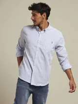 Camisa de manga larga con patrón de rayas verticales celestes y blancas, corte regular fit, cuello con botones y un bolsillo en el pecho con logo bordado.