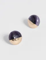 Par de aros tipo botón con forma de semiesfera, con la mitad superior de piedra natural color amatista y la mitad inferior de metal dorado.