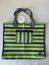Bolso tipo tote de playa con diseño de rayas horizontales en colores verde, azul, amarillo y blanco. Cuenta con un bolsillo frontal aplicado, doble asa de hombro y el logo de la marca bordado en la esquina inferior.