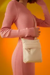 Bandolera pequeña color beige, de poliéster, con correa larga regulable y bolsillo frontal con cierre.