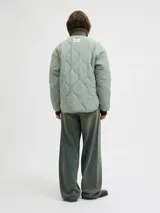 Campera acolchada de color gris oscuro, con diseño matelaseado de ondas, cuello alto en rib, cierre frontal con cremallera metálica y bolsillos frontales aplicados.