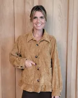 Sobrecamisa de pana color mostaza, con cuello camisero, cierre frontal de botones y volado en el ruedo. Presenta bolsillos frontales y mangas largas con puños abotonados.