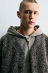 Cárdigan de corte relajado confeccionado en tejido con textura efecto pelo. Presenta cuello en pico, manga larga, cierre frontal con botones y bolsillos delanteros tipo plastrón. Los puños y el bajo cuentan con acabado en rib.
