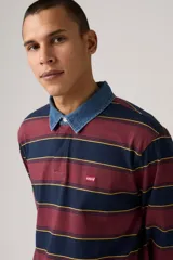 Remera tipo polo de manga larga con diseño a rayas horizontales en tonos bordó, azul marino y amarillo. Presenta cuello de denim con cierre de botones y pequeño logo de la marca en el pecho.