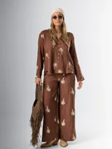 Conjunto de camisa y pantalón marrón chocolate con bordados en hilo crudo. El pantalón lleva elástico en la cintura.