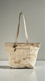 Cartera tipo tote bag de cuero natural con diseño artístico pintado a mano, doble asa de hombro y detalle de dije colgante metálico.