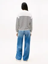 Sweater Tommy Jeans de algodón regenerativo a rayas horizontales blancas y azules, con cuello redondo y logo bordado en el pecho y en el puño.