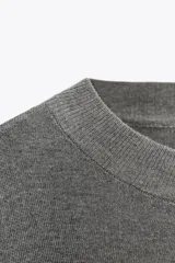 Jersey de punto gris jaspeado, de corte oversize, con cuello redondo y mangas cortas amplias.