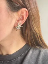 Aros caravanas plateados con diseño de estrella de mar y detalle en espiral en el centro.
