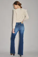 Jean de corte acampanado con tiro alto, confeccionado en denim azul con lavado medio y costuras a tono.