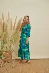 Vestido midi con estampado abstracto en tonos verdes y azules, cuello redondo, mangas tres cuartos y lazo ajustable en la cintura.