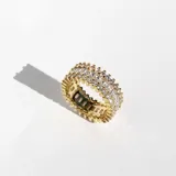 Anillo dorado con tres hileras de cristales blancos de diferentes tamaños.
