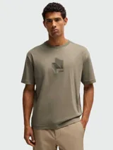 Camiseta negra de corte relajado con cuello redondo y manga corta. Presenta un diseño tridimensional en el pecho que simula un pliegue o estructura geométrica en tono negro brillante o texturizado.